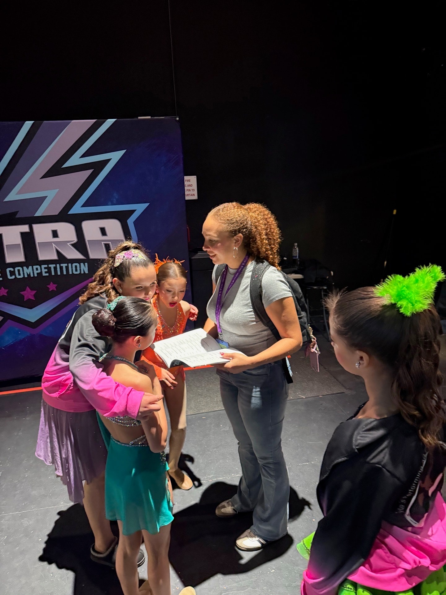Instructor reviewing scores with dancers backstage at Ultra Dance Competition