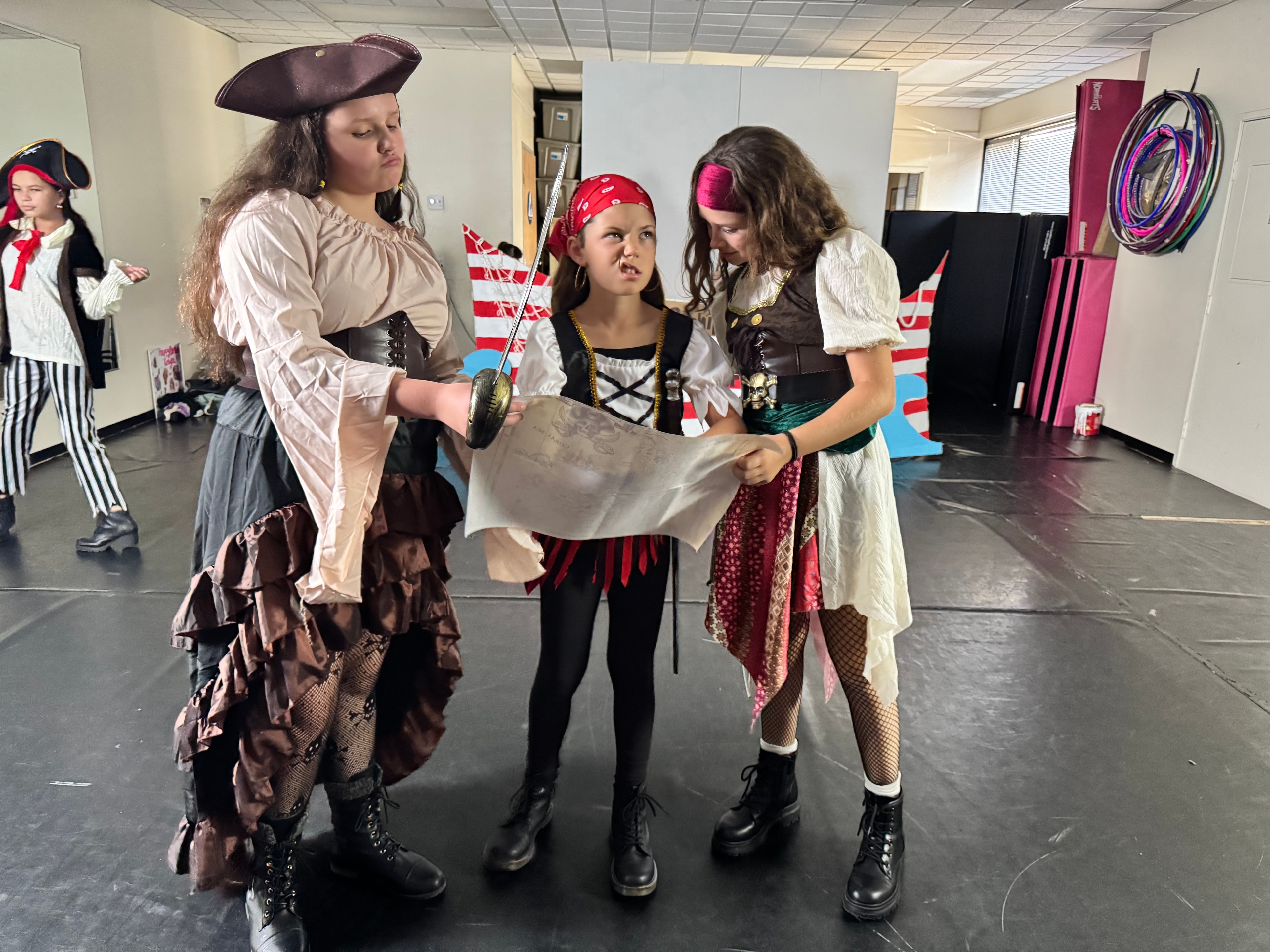 Three pirates reading a treasure map on stage