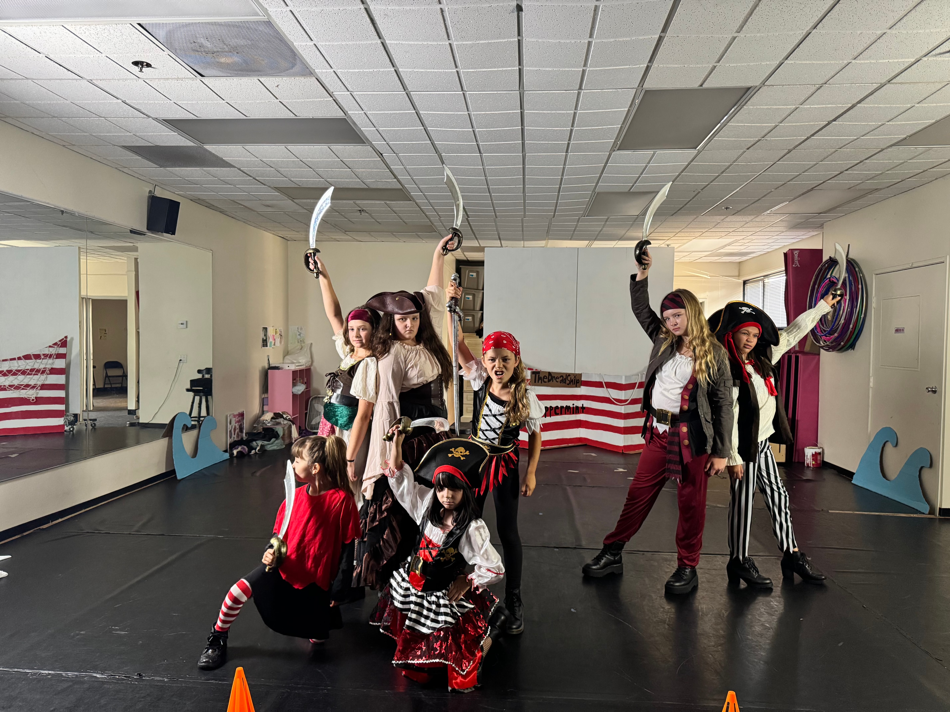 KPAC pirate cast posing with swords raised