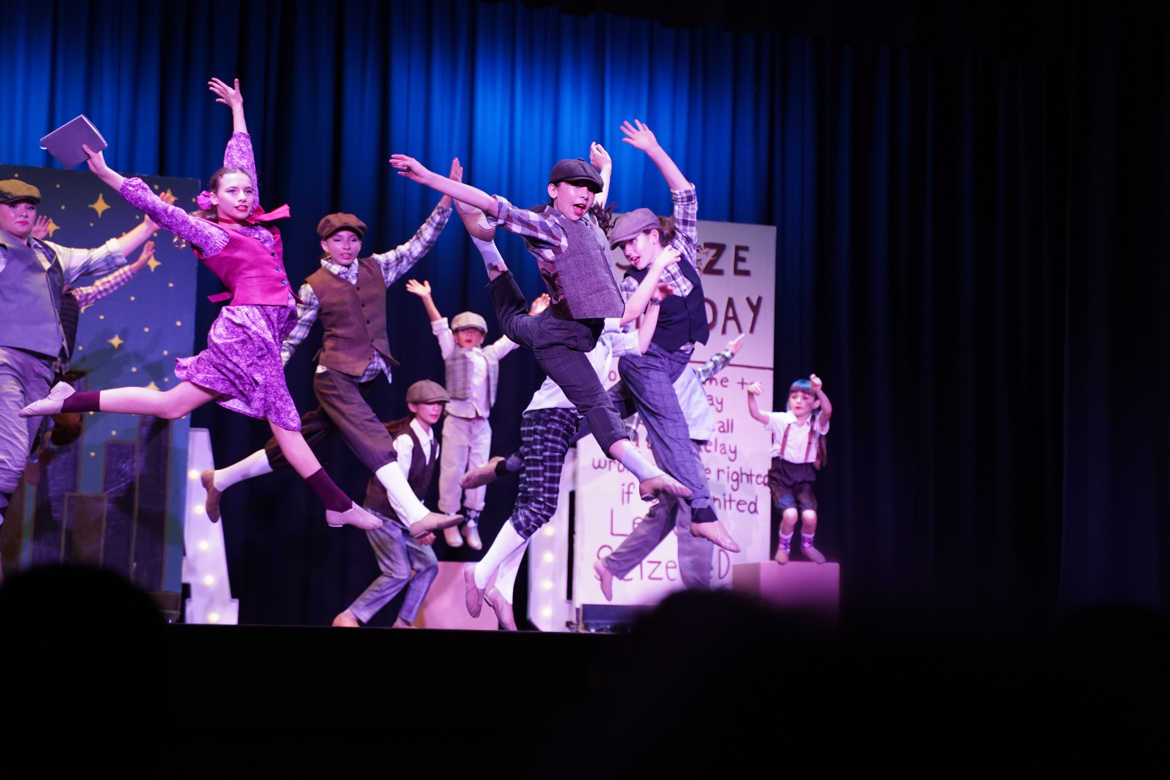 KPAC dancers leaping mid-air in Newsies